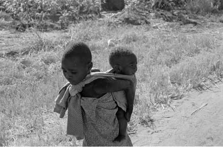 Maedchen in
                Afrika mit ihrem Bruder auf den Ruecken gebunden