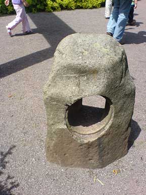 Steinskulptur mit Kreis und Quadrat, Beine von
                Passanten, Schatten