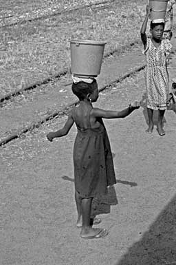 Kleines Maedchen als Wasserverkaeuferin am
                Bahnsteig in Kamerun
